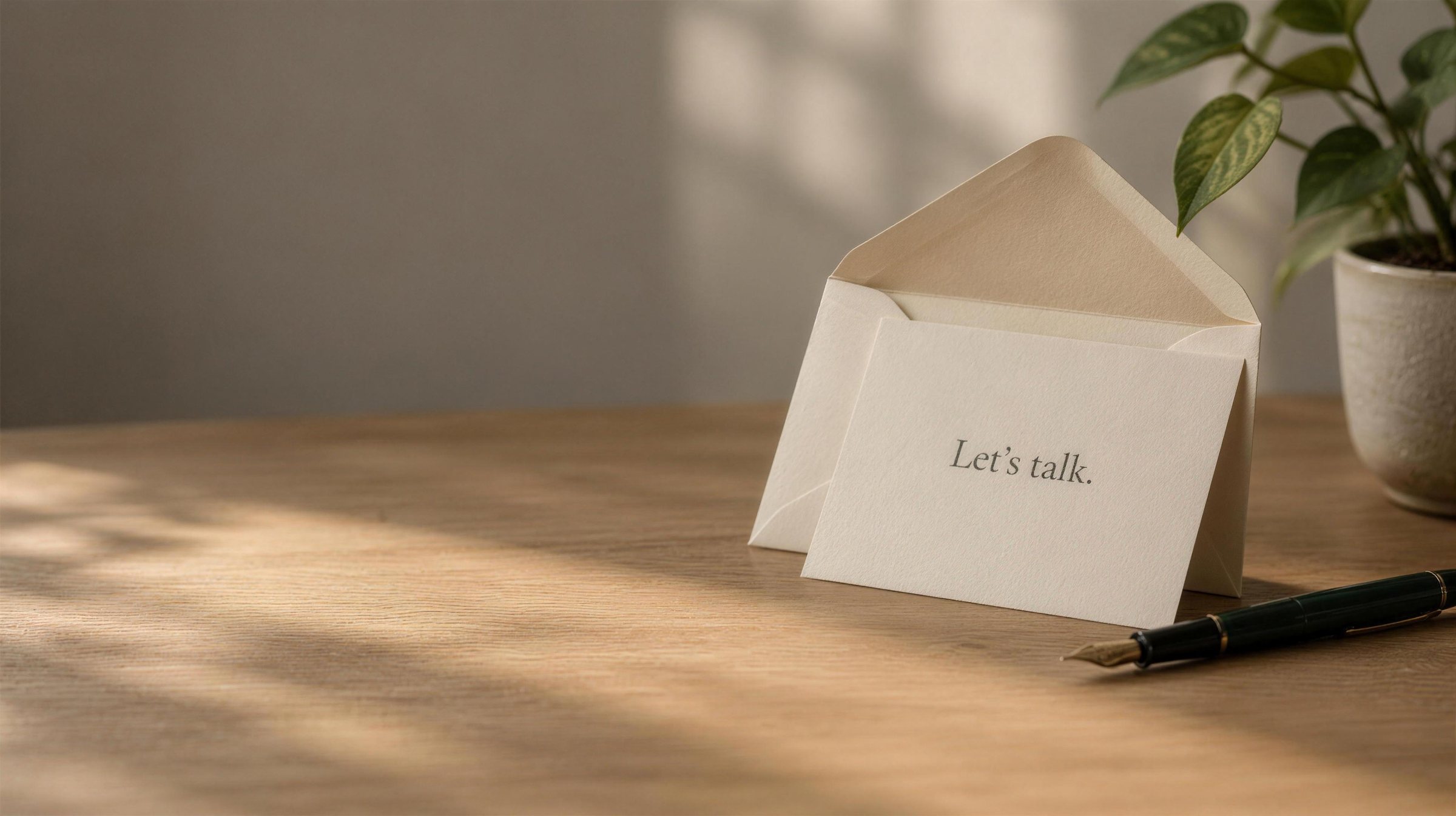 An opened envelope with a reply card that reads Let's talk, on a sunlit desk